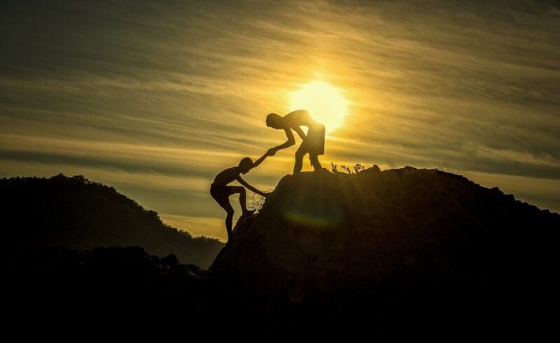 sunset men sinhouettes helping helping hand