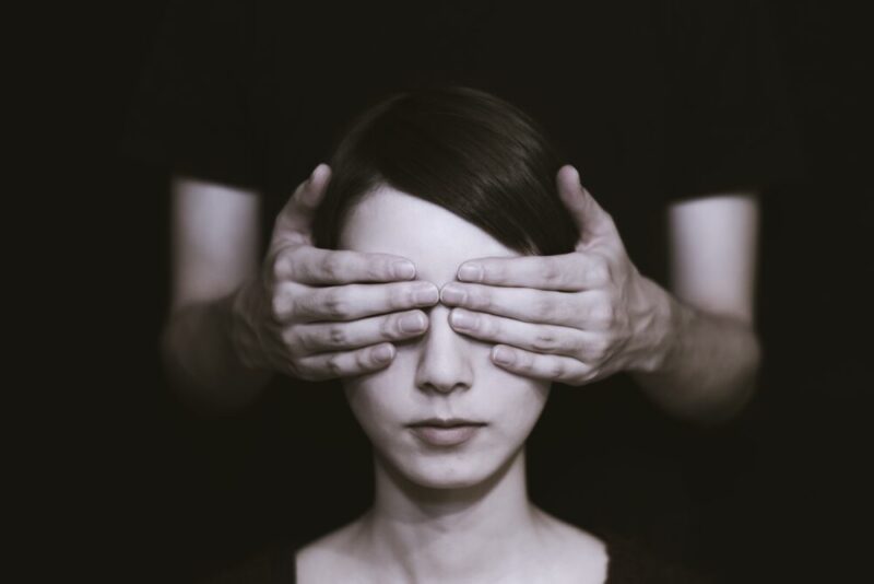 person covering the eyes of woman on dark room photo