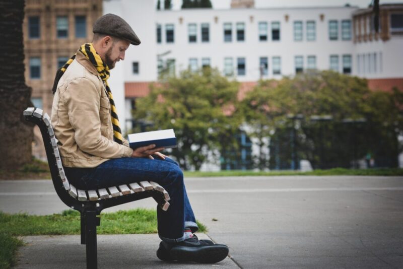 uncle sitting on an outdoor bench reading a book