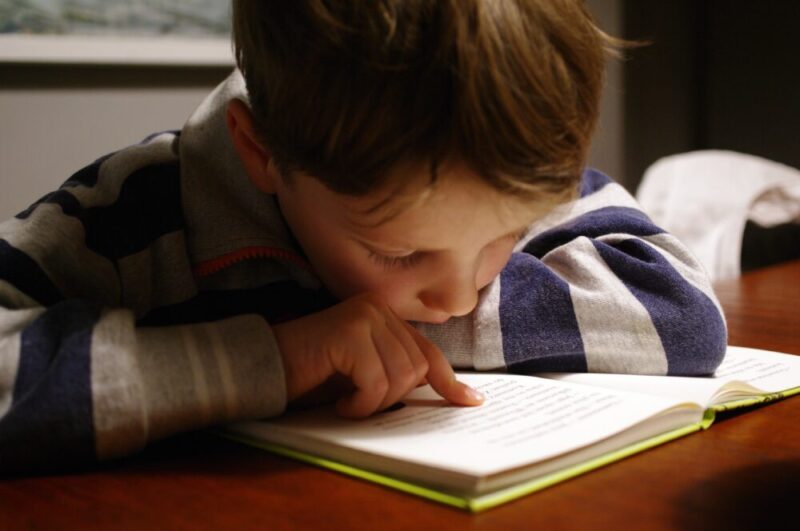 boy reading a book wearing a gray hoodie